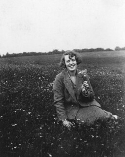 Image of Barbara Pym in a field holding a flower