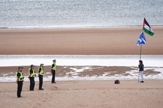 Police officers and a protester on Balmedie Beach ahead of Donald Trump’s visit to his Menie golf course in Aberdeenshire, 28 July 2025. (PA / Jane Barlow)