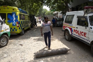 A man in New Delhi rolls an oxygen cylinder after waiting more than eight hours for it to be refilled. Photograph © Ishan Tankha